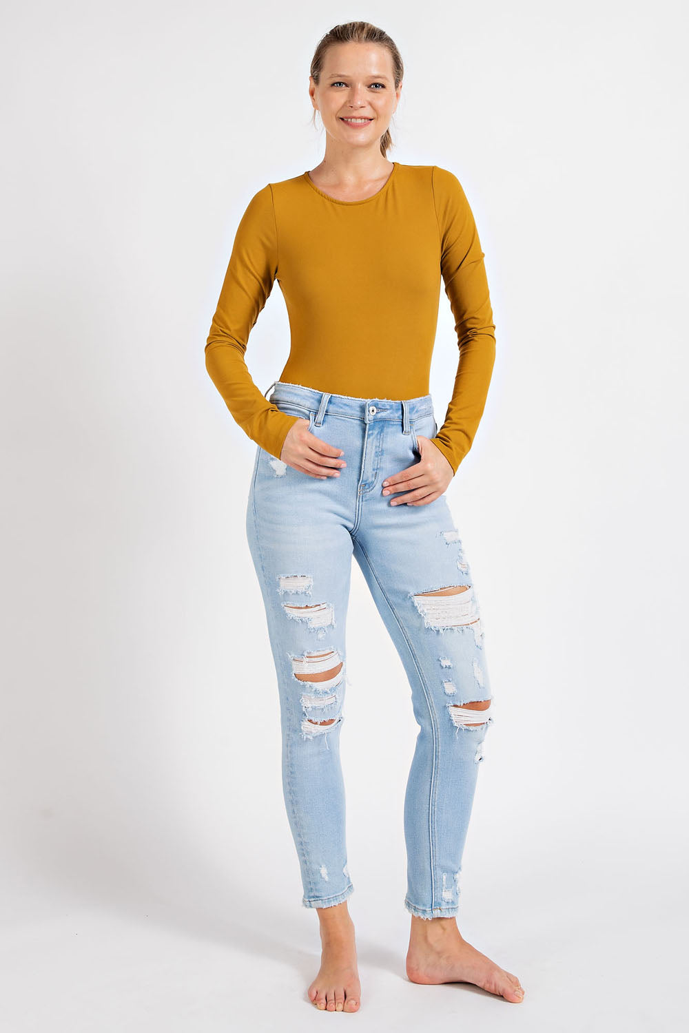“Chambray Butter Round Neck Long Sleeve Bodysuit by Rae Mode”
“Gold Spice long sleeve buttery soft bodysuit laid flat showing round neck & snap closures”
“Model wearing Rae Mode bodysuit paired with jeans showing clean silhouette”