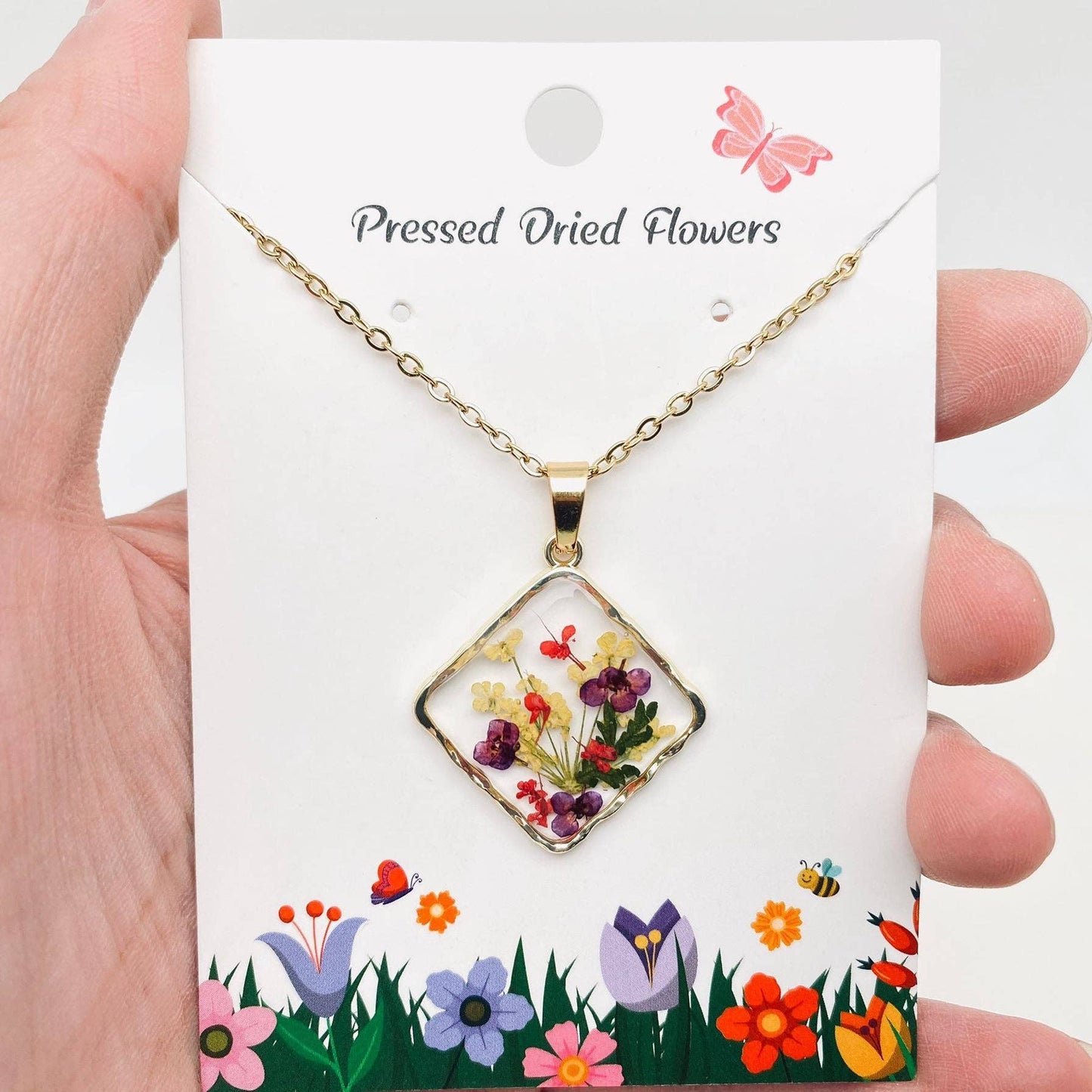 Square pendant necklace with pressed floral arrangement in resin
Close-up of dried flowers encased in clear resin square frame
Necklace styled over neutral top showing copper frame & stainless steel chain