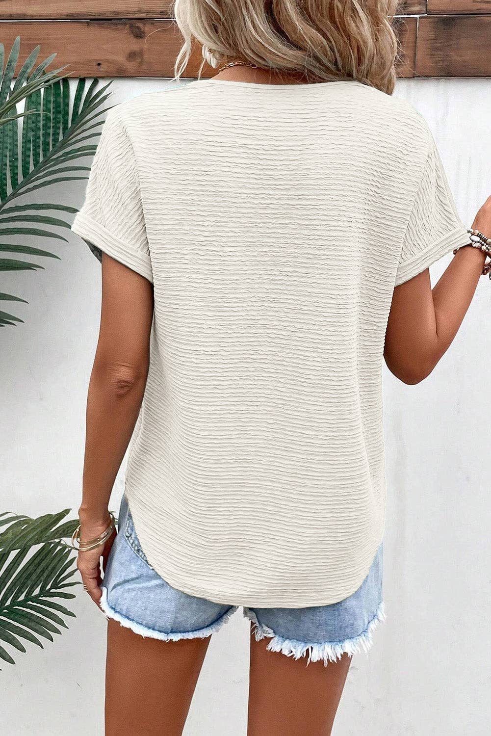 Pale khaki textured V‑neck tee on hanger showing wide sleeves