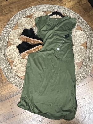 A green short sleeve maxi dress displayed on a mannequin with accessories including earrings and booties.