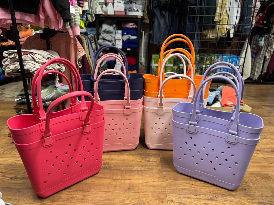 A selection of colorful tote bags displayed in a retail setting, featuring a solid pattern with perforations and multiple handles.