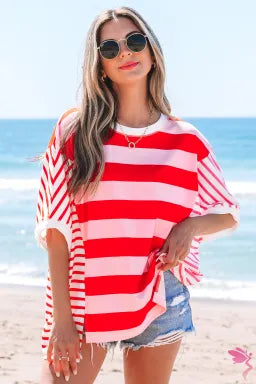 A woman wearing a red and pink striped patchwork t-shirt with a round neckline, loose fit, and side split design.