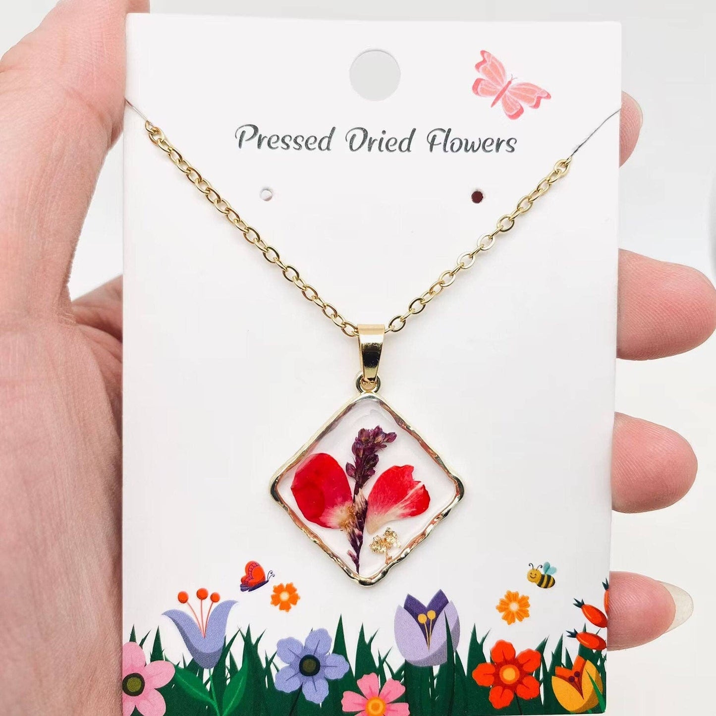 Square pendant necklace with pressed floral arrangement in resin
Close-up of dried flowers encased in clear resin square frame
Necklace styled over neutral top showing copper frame & stainless steel chain