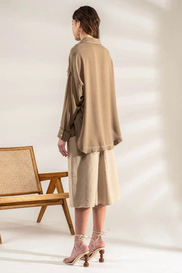 Olive oversized button-down shacket with frayed hem laid flat
Close-up of contrast stitching and chest pocket tab detail
View of raw hem edge and drape of oversized silhouette