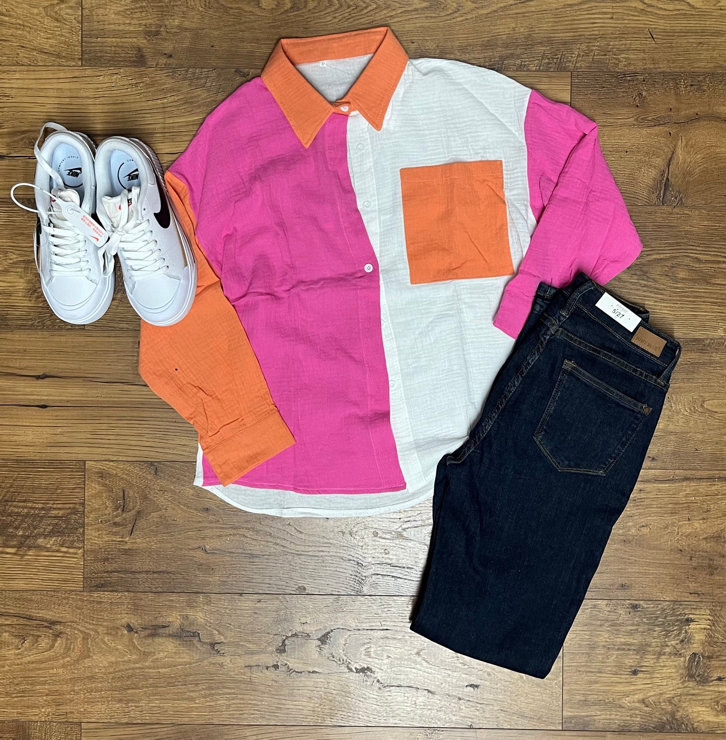 An oversized colorblock linen button-up shirt laid out flat with white sneakers and black jeans.