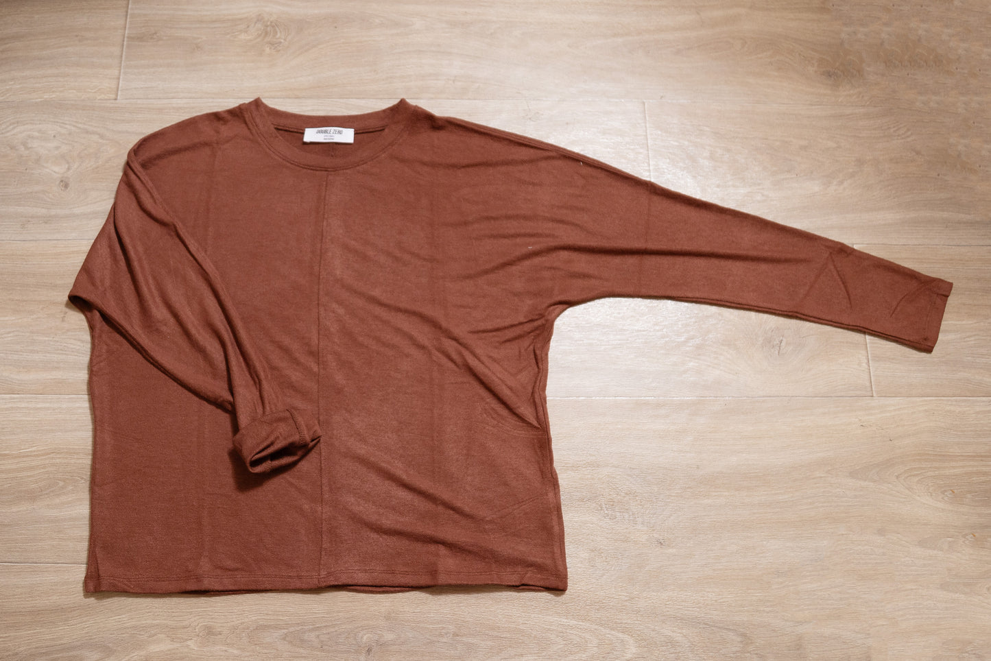 Brown long-sleeve shirt on a wooden floor
