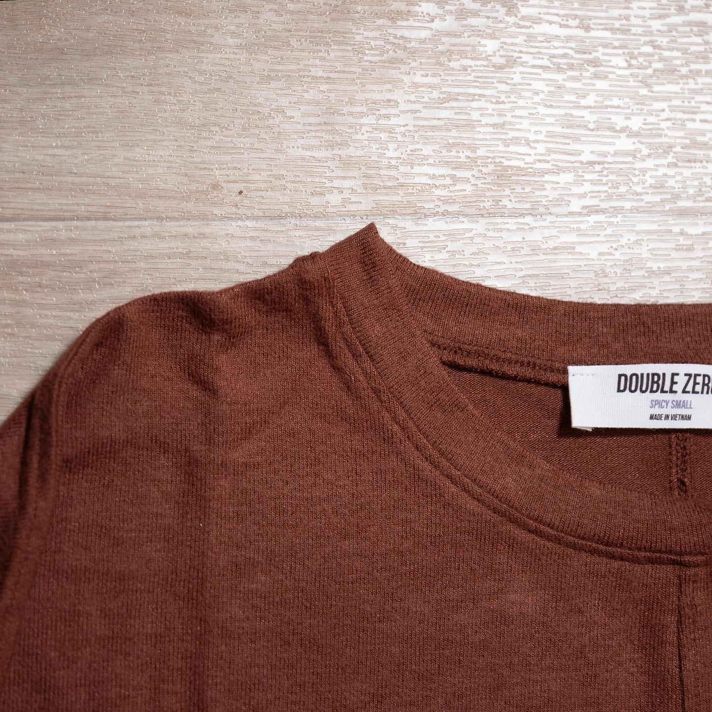 Brown shirt with a visible brand label on a wooden surface