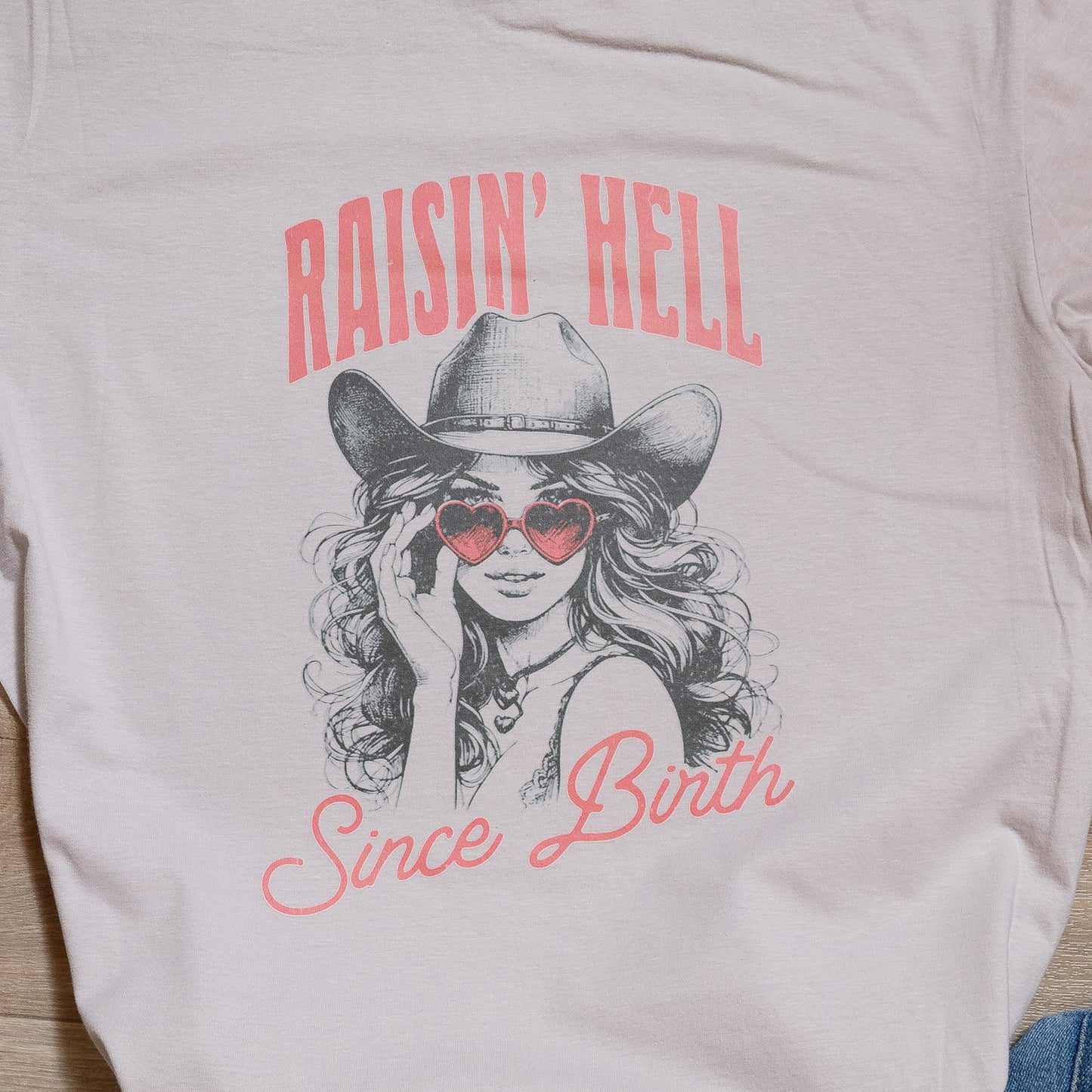 Raisin’ Hell Since Birth Graphic Tee – Western Cowgirl T-Shirt with Heart Sunglasses