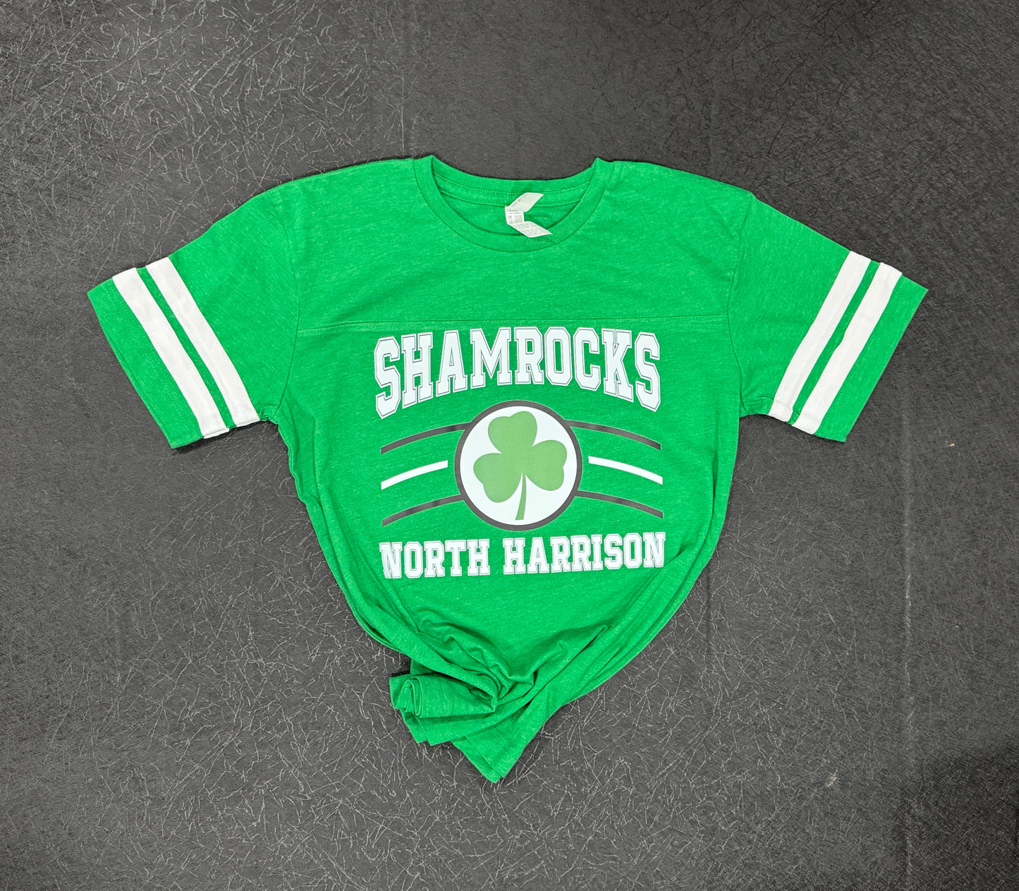 Classic Sport neutral vintage shamrock t‑shirt front view – local mascot graphic tee
Classic Sport neutral vintage shamrock t‑shirt back view – soft cotton crew neck shirt
Classic Sport neutral vintage shamrock t‑shirt styled outfit – retro mascot tee look
Classic Sport neutral vintage shamrock t‑shirt fabric close‑up – vintage graphic cotton texture
Classic Sport neutral vintage shamrock t‑shirt flat lay – neutral mascot pride tee