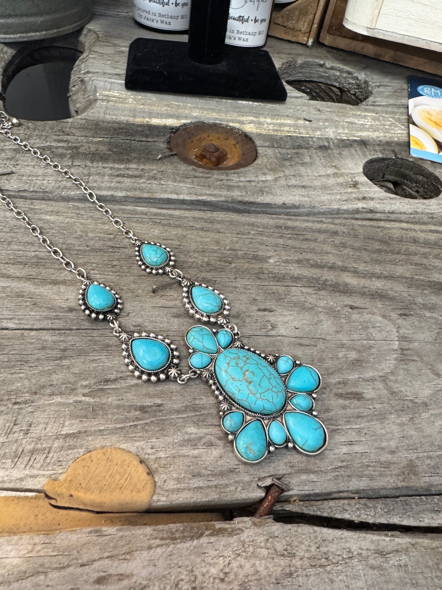 A turquoise necklace and earring set with silver accents displayed on a wooden surface.
