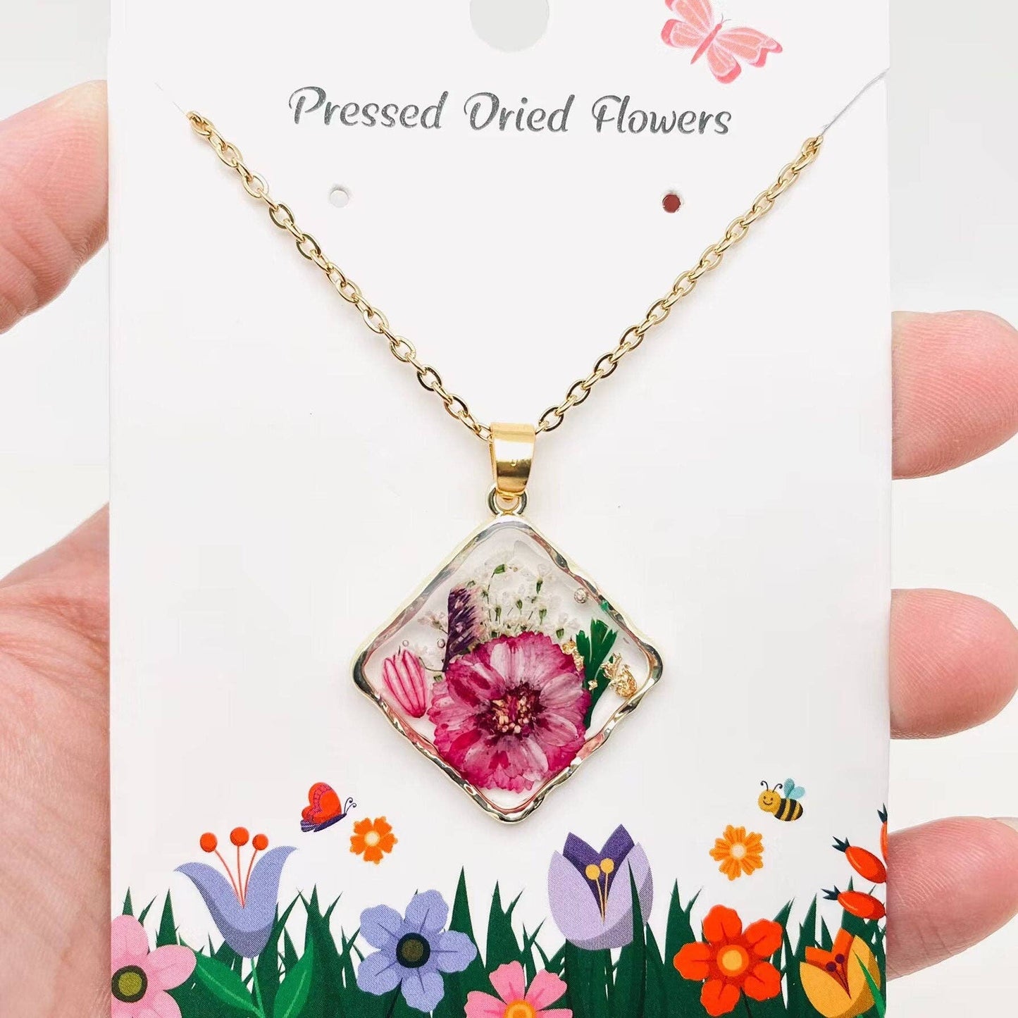 Square pendant necklace with pressed floral arrangement in resin
Close-up of dried flowers encased in clear resin square frame
Necklace styled over neutral top showing copper frame & stainless steel chain