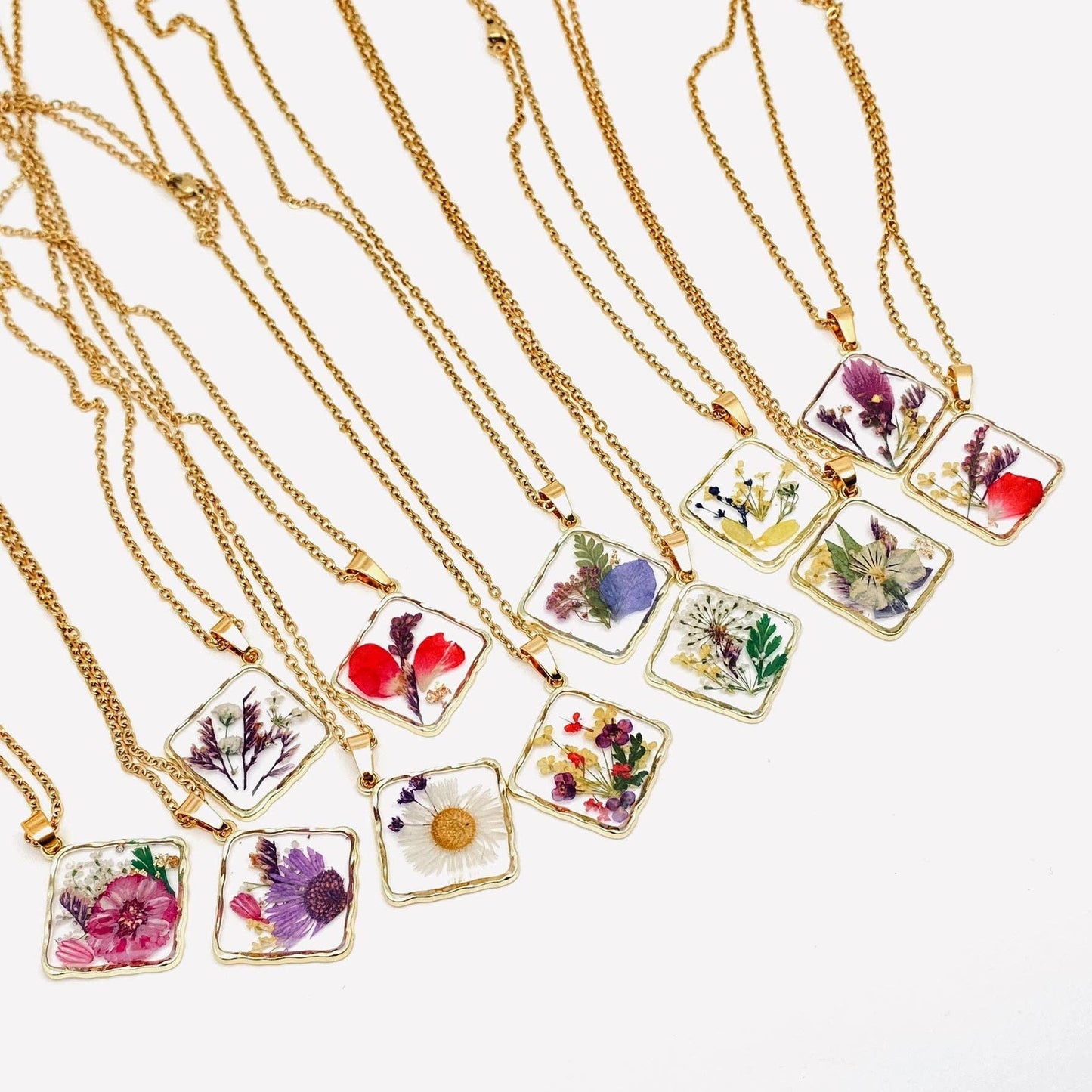 Square pendant necklace with pressed floral arrangement in resin
Close-up of dried flowers encased in clear resin square frame
Necklace styled over neutral top showing copper frame & stainless steel chain