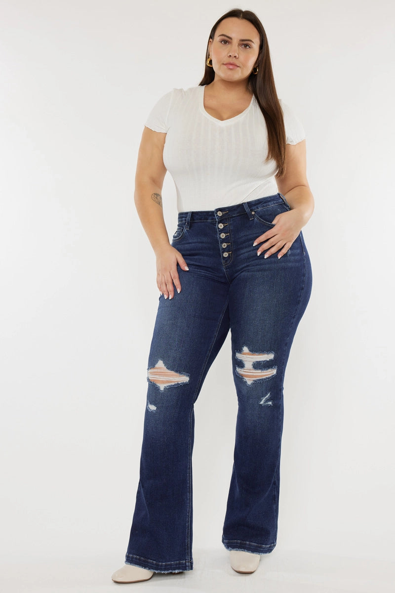 A model wearing a mid-rise distressed flare jean in a dark stone wash with an exposed button fly and five pocket style.