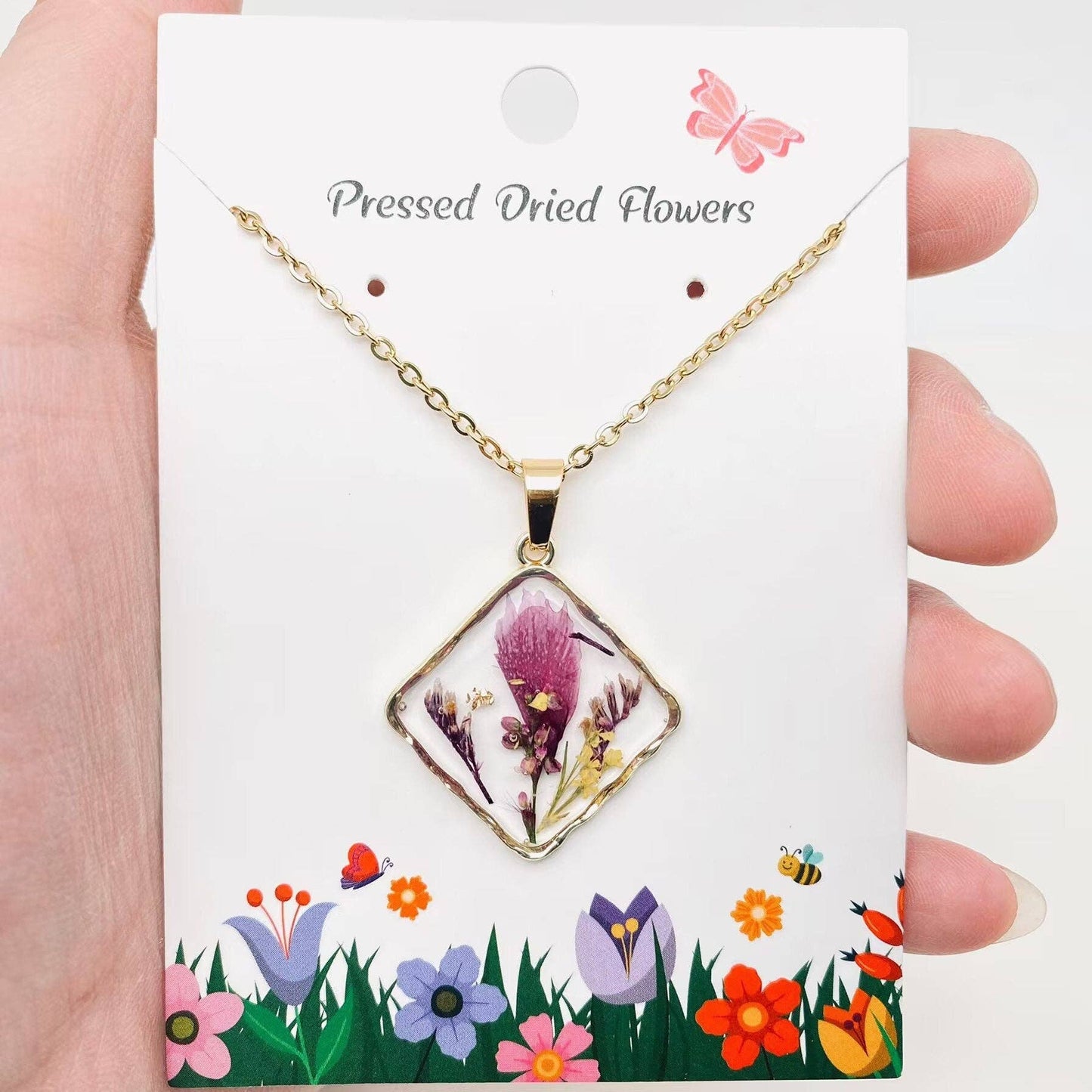 Square pendant necklace with pressed floral arrangement in resin
Close-up of dried flowers encased in clear resin square frame
Necklace styled over neutral top showing copper frame & stainless steel chain