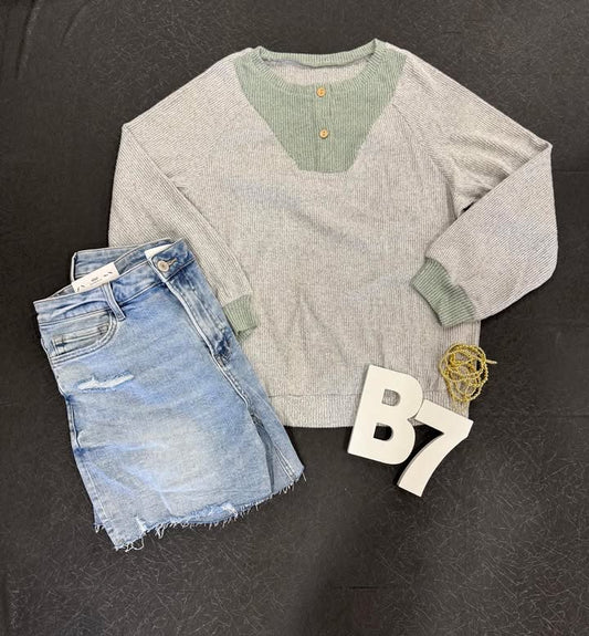 Grey Ribbed Top – front view – Light grey ribbed loose-fit long sleeve top with contrast details.
Grey Ribbed Top – back view – Relaxed fit ribbed long sleeve pullover in light grey.
Grey Ribbed Top – styled outfit – Model wearing light grey ribbed long sleeve top with denim.
Grey Ribbed Top – close-up fabric detail – Ribbed knit texture with color contrast seam.
Grey Ribbed Top – layered look – Grey ribbed top styled with accessories for a casual chic outfit.