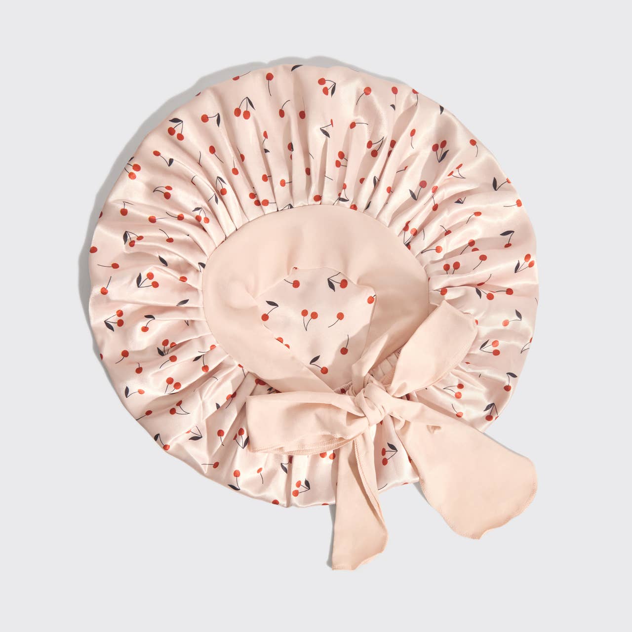 Beige shower cap with cherry pattern on a light gray background