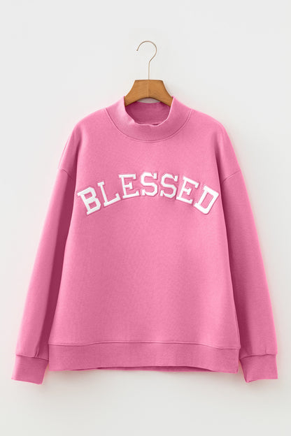 Pink sweatshirt with 'BLESSED' text on a hanger against a white background