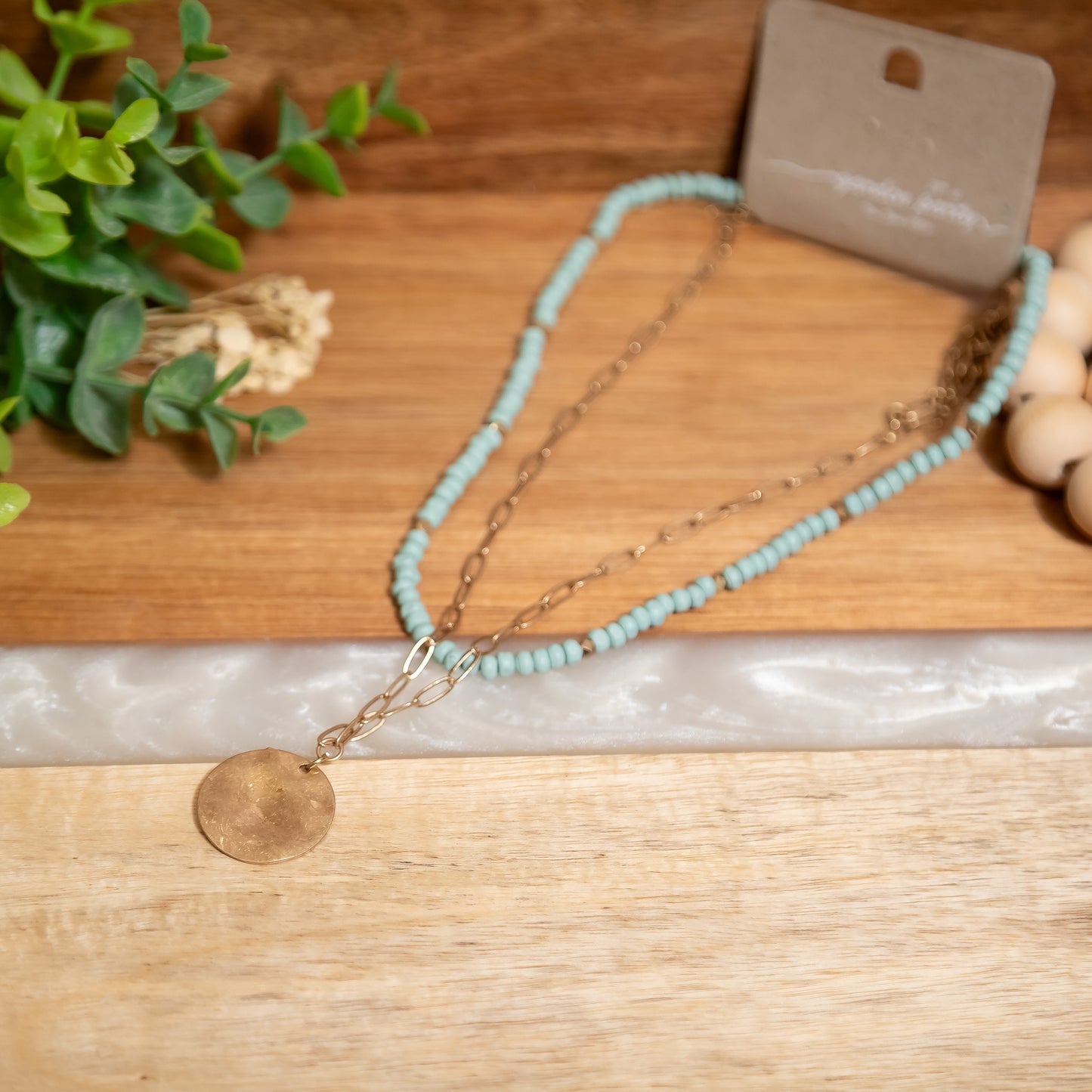 Necklace with turquoise beads and gold chain on a wooden surface