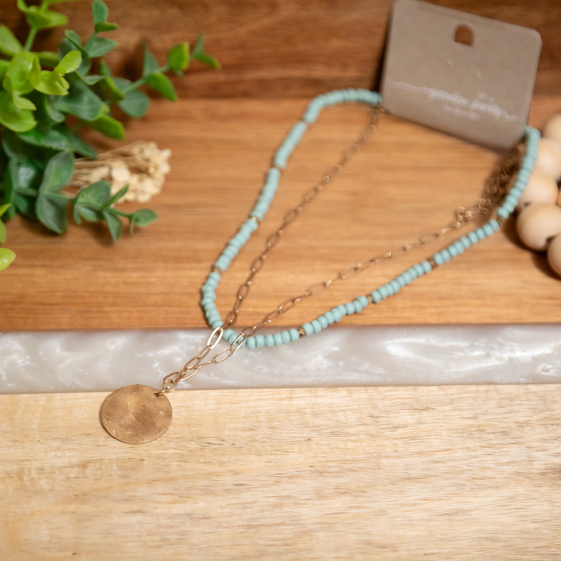 Necklace with turquoise beads and gold chain on a wooden surface
