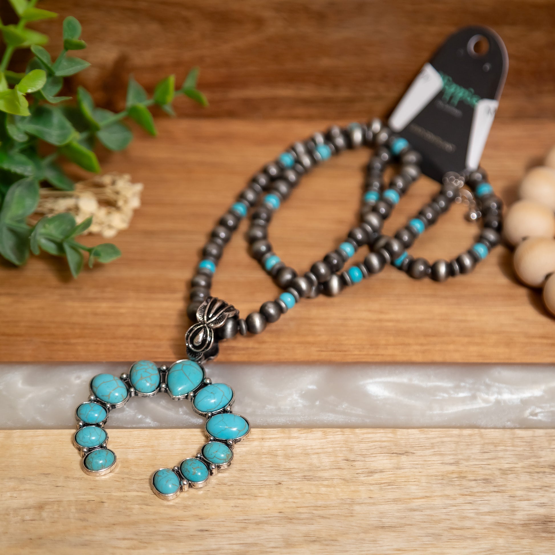 Necklace with turquoise stones and silver pendant on a wooden surface
