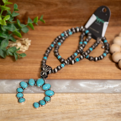 Necklace with turquoise stones and silver pendant on a wooden surface