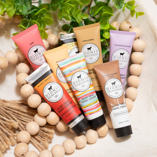 Collection of Dionis hand cream tubes with various scents on a decorative background with wooden beads and greenery.