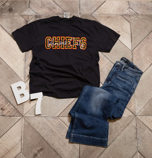 Black t-shirt with 'CHIEFS' text and blue jeans on a tiled floor.