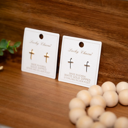 Two pairs of cross-shaped earrings on 'Lucky Charm' cards with wooden beads in the foreground.