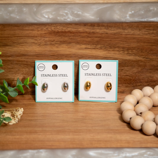 Two pairs of stainless steel earrings on display with a wooden background