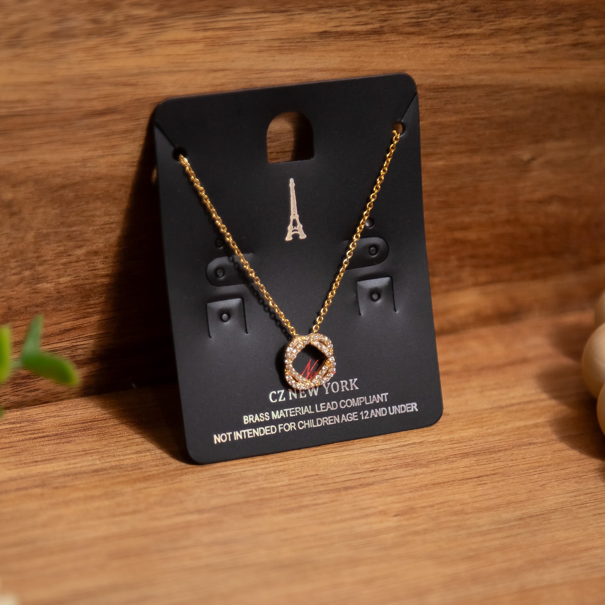Gold necklace on a black card with Eiffel Tower design on a wooden surface