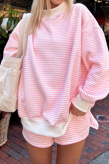 Person wearing a pink and white striped outfit with a beige bag on a street.