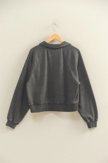 “Raglan sleeve sweatshirt with collar and placket laid flat on wooden floor”